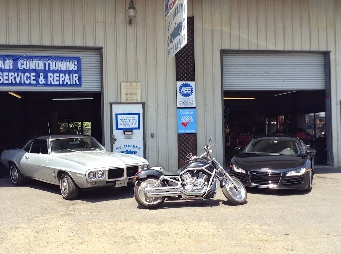 A classic Pontiac Firebird, a motorcycle and an Audi R8 parked outside the service bays.